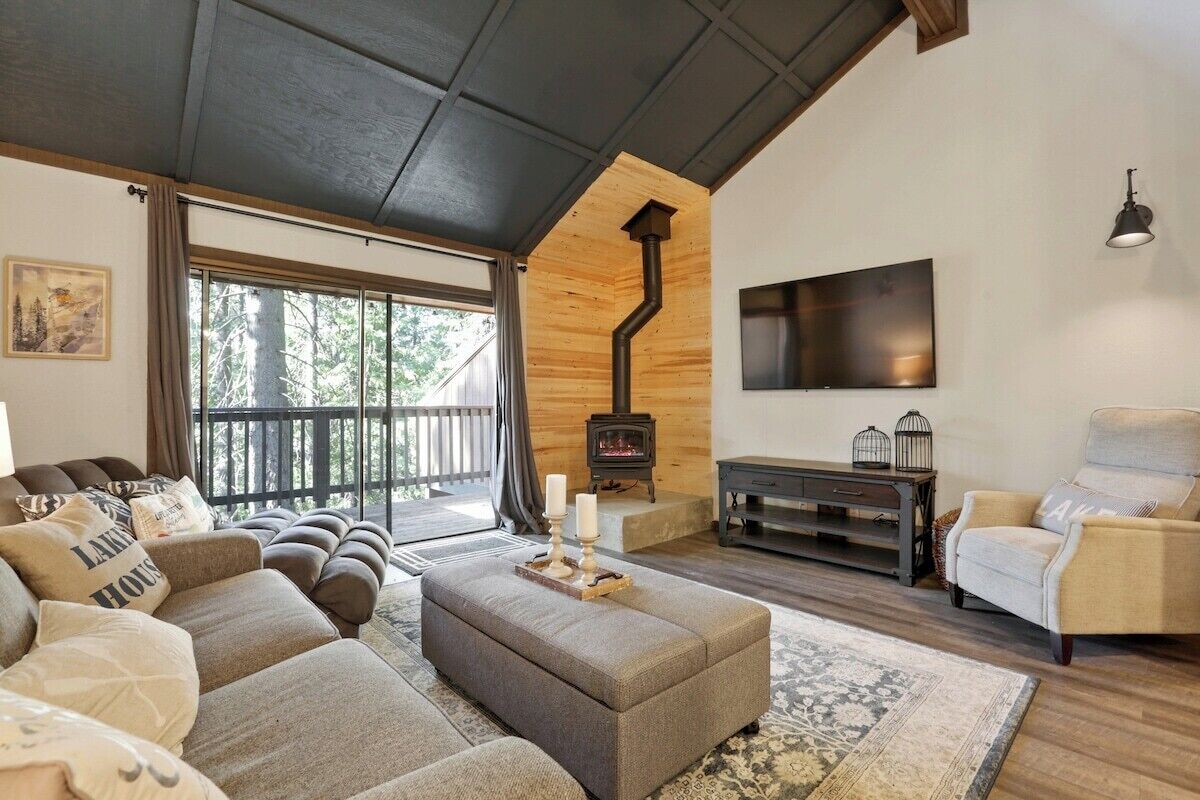 A cozy living room with a fireplace, comfortable seating, and a large window.