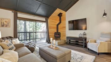 A cozy living room with a fireplace, comfortable seating, and a large window.