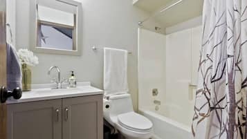 A bathroom with a toilet, sink, and shower area.