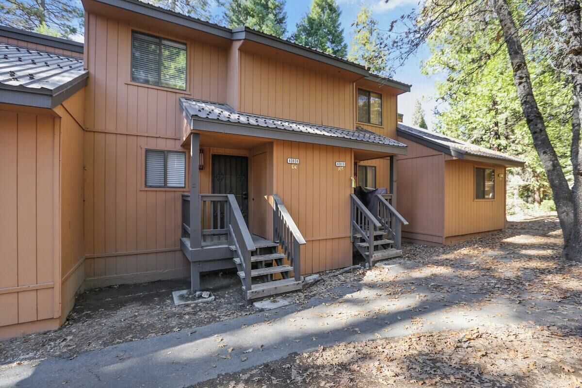 A two-story wooden cabin with a porch, a staircase, and a small attached shed.