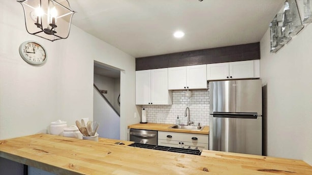 A modern kitchen with a wooden island, stainless steel appliances, and white cabinetry. - Shaver Escape! Mountain Loft Condo (Shaver Lake)