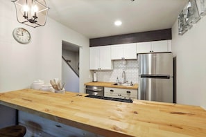 A modern kitchen with a wooden island, stainless steel appliances, and white cabinetry. - Shaver Escape! Mountain Loft Condo (Shaver Lake)
