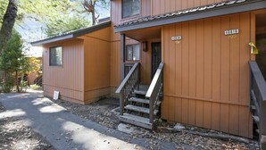 A two-story wooden cabin with a porch and a staircase leading to the entrance. - Shaver Escape! Mountain Loft Condo (Shaver Lake)