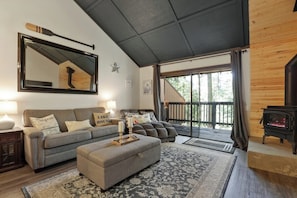 A cozy living room with a sofa, ottoman, and a fireplace. - Shaver Escape! Mountain Loft Condo (Shaver Lake)