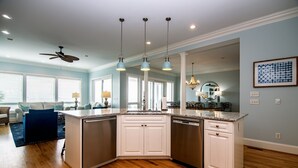 A modern kitchen with white cabinets, a granite countertop, and a ceiling fan. - Oceanfront Showplace w/ Private Pool & Elevator; Expansive Beach & Ocean Views; Multiple Porches (Edisto Island)