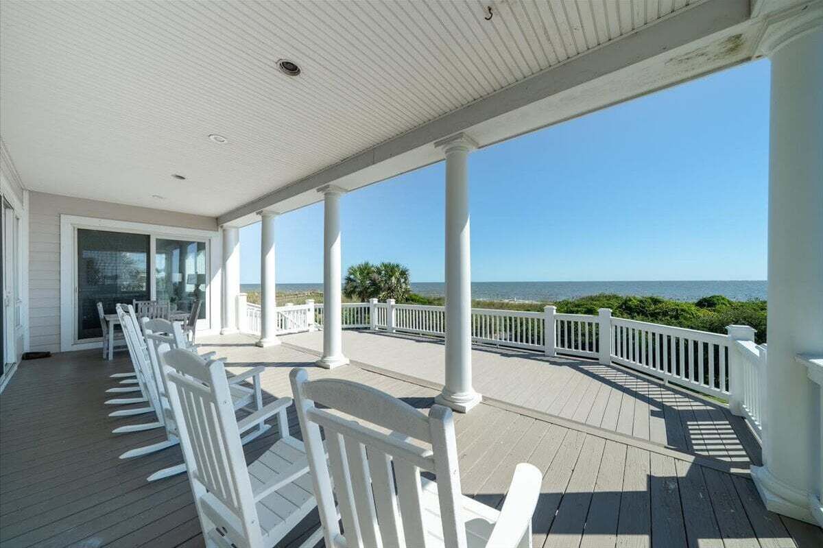 A covered porch with white railings and a view of the ocean.