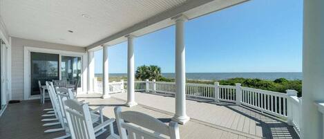 A covered porch with white railings and a view of the ocean.