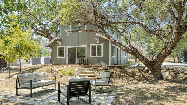 A modern house with a patio area featuring a sofa and chairs. - Riverfront Gateway to Sequoia NP (Three River)