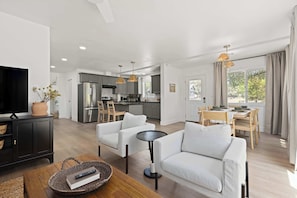 A modern living room with a TV, sofa, and dining area. - Riverfront Gateway to Sequoia NP (Three River)