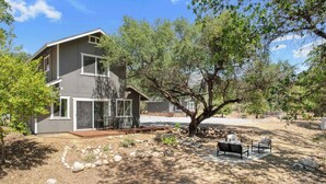 A two-story house with a patio area, a tree, and outdoor furniture. - Riverfront Gateway to Sequoia NP (Three River)