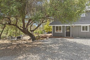 A house with a gravel driveway, a front porch, and a large tree in the background. - Riverfront Gateway to Sequoia NP (Three River)