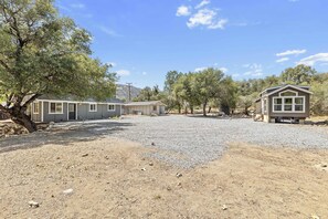A residential area with multiple houses, a gravel driveway, and sparse vegetation. - Riverfront Gateway to Sequoia NP (Three River)
