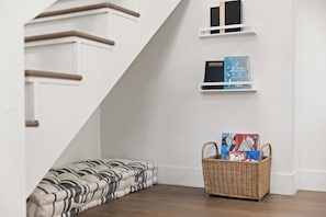 A staircase with a bench, a wicker basket with snacks, and books on shelves.