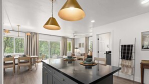 A modern kitchen with a central island, pendant lighting, and a view of the outdoors. - Riverfront Gateway to Sequoia NP (Three River)