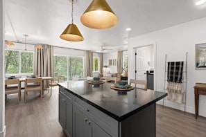 A modern kitchen with a central island, pendant lighting, and a view of the outdoors.