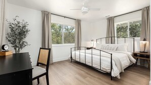 A bedroom with a bed, a desk, a chair, a plant, and a window with curtains. - Riverfront Gateway to Sequoia NP (Three River)