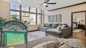 A spacious living room with a sectional sofa, a ceiling fan, and a large window.