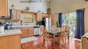 Une cuisine avec des meubles de rangement en bois, un réfrigérateur, une cuisinière et une table à manger avec des chaises.