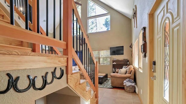Un vaste espace de vie comprenant un escalier en bois, un canapé et un téléviseur.