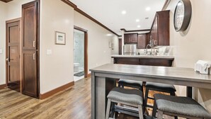 Una cocina con armarios de madera, un refrigerador de acero inoxidable y una zona de bar con taburetes.
