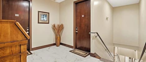 Un vestíbulo de hotel con suelo de mármol, puertas de madera, un mostrador de recepción y un cuadro en la pared.