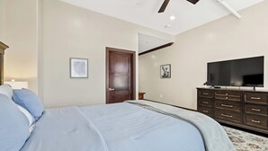 A bedroom with a bed, a dresser, a television, and a door. - Midtown Loft 301 on Main St DT Visalia (Visalia)