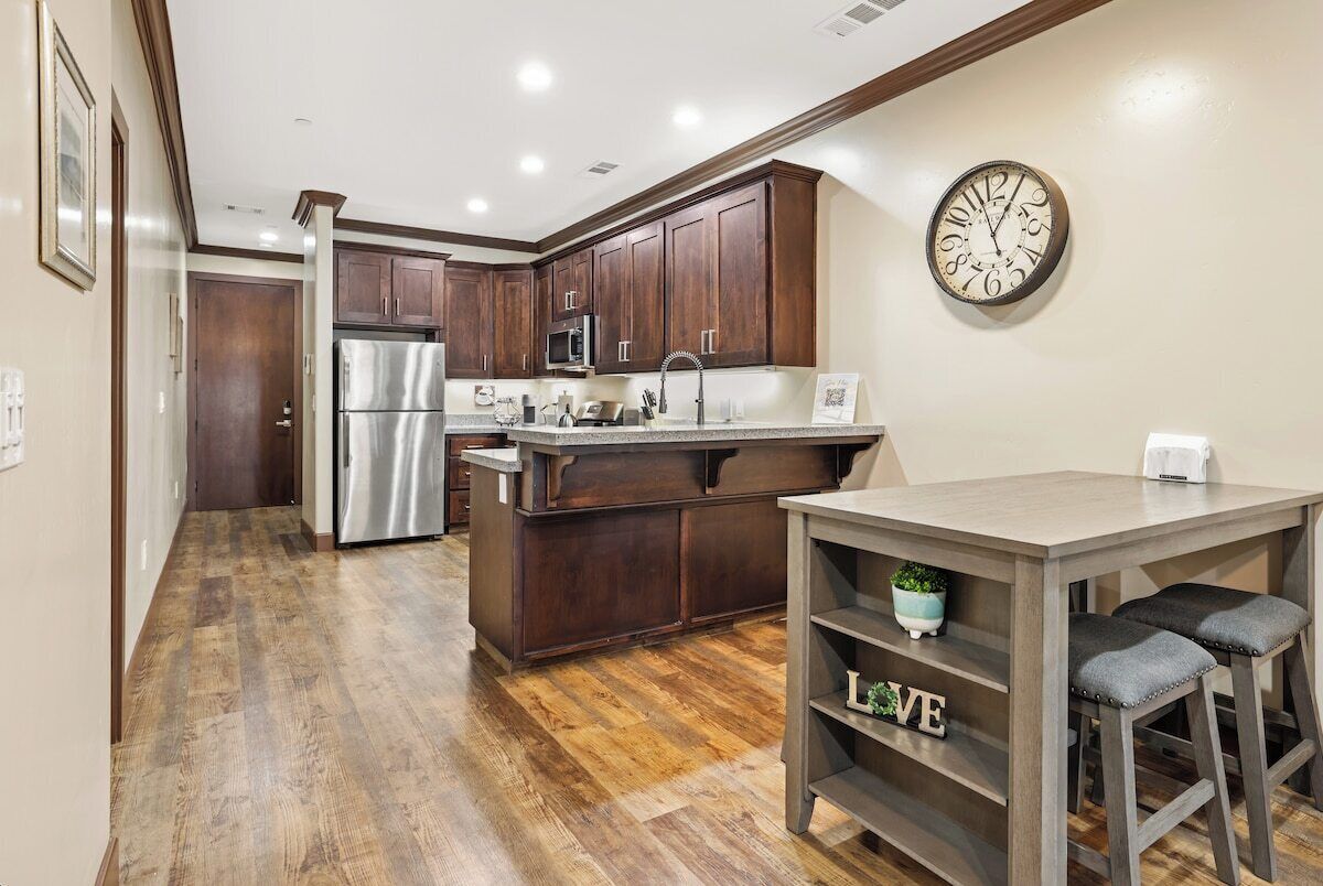 A kitchen with wooden cabinets, stainless steel appliances, and a clock on the wall.