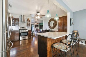 A modern kitchen with stainless steel appliances, a wooden island, and hanging pendant lights.
