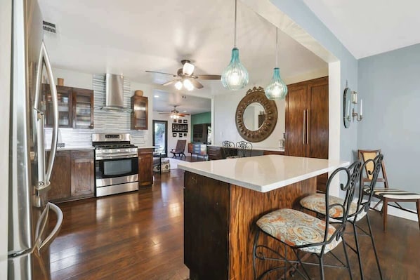 A modern kitchen with stainless steel appliances, a wooden island, and hanging pendant lights.