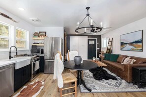 Une cuisine moderne avec un coin repas, une cheminée et un salon comprenant un canapé et un tableau.