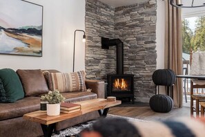Un salon chaleureux avec une cheminée en pierre, un canapé en cuir, une table basse en bois et un tableau accroché au mur.