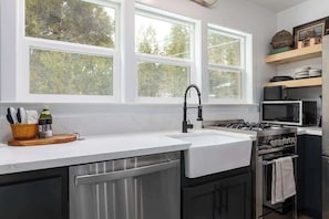 Una cocina moderna con un ventanal grande, electrodomésticos de acero inoxidable y una tabla de cortar de madera con utensilios.