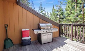 Un área de parrilla al aire libre con cubierta de madera, una pala de tierra y un refrigerador.