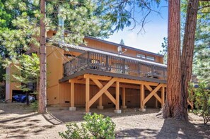 A wooden cabin with a balcony, surrounded by trees.