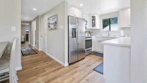 Una cocina moderna con armarios blancos, electrodomésticos de acero inoxidable y piso de madera.