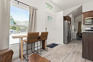 A modern kitchen with a refrigerator, microwave, and wooden cabinets. - Tiny River House w River Frontage (Three River)