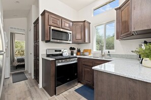 A modern kitchen with dark wood cabinets, stainless steel appliances, and a large window providing natural light.