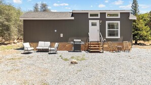 A single-story building with a patio area, outdoor seating, and a grill.