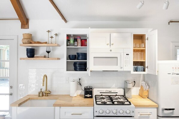 A kitchen with white cabinets, a gas stove, a microwave, and a toaster.