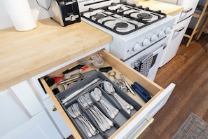 A kitchen with a white stove, a drawer with utensils, and a wooden countertop. - Downtown Retreat w/ Pool & Spa, Near National Parks (Visalia)