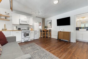 A modern kitchen with white cabinets, a microwave, and a stove. There's a dining area with a table and chairs. - Downtown Retreat w/ Pool & Spa, Near National Parks (Visalia)