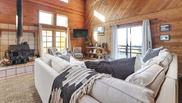 A cozy cabin interior with a fireplace, comfortable seating, and wooden walls.