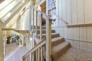A multi-level interior with a staircase, wooden paneling, and a view of the lower level. - Sierra Nevada Cabin: Arcade & Jacuzzi (Shaver Lake)