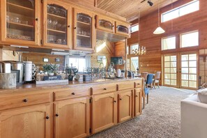 A spacious kitchen with wooden cabinets and a large island, featuring a coffee station and various kitchen appliances. - Sierra Nevada Cabin: Arcade & Jacuzzi (Shaver Lake)
