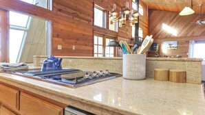 A kitchen with wooden walls, a granite countertop, and a stove.