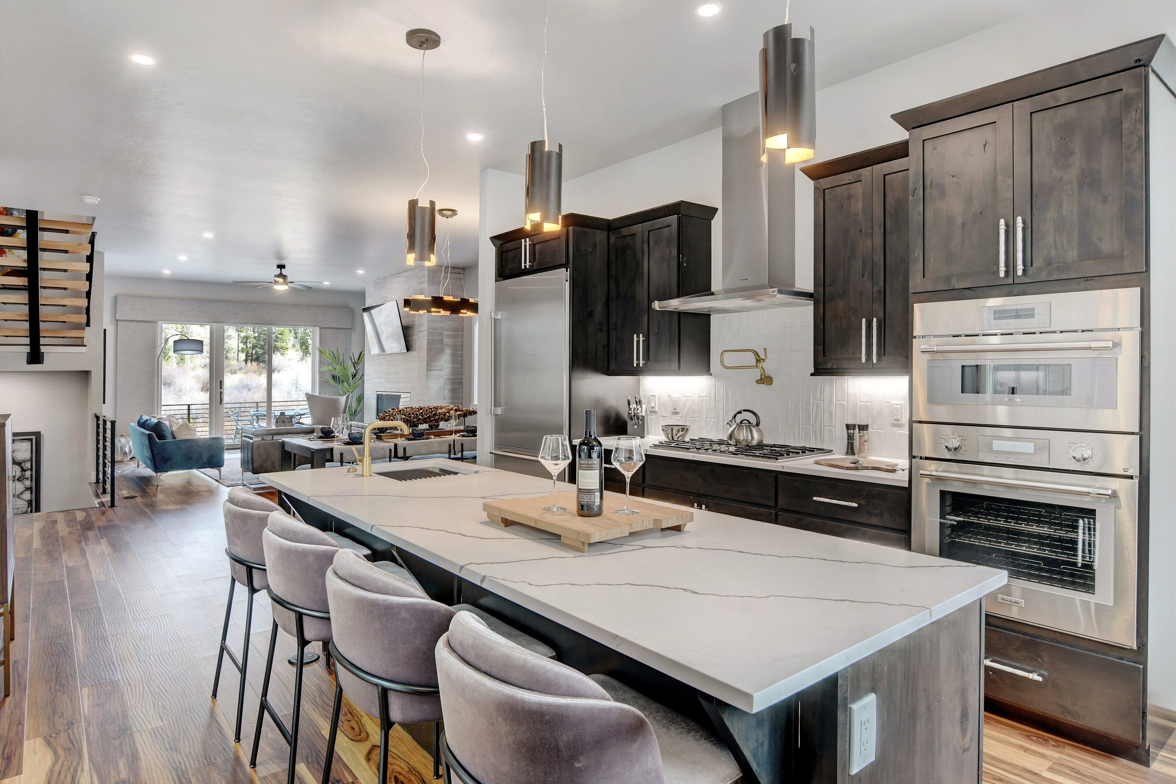 A modern kitchen with a large island, stainless steel appliances, and dark wood cabinets.