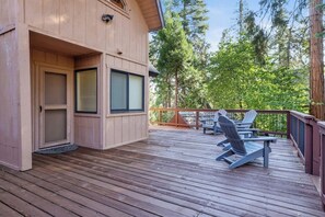 A wooden deck with Adirondack chairs and a wooden building with large windows.