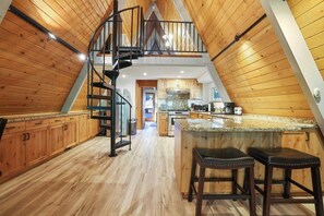 Eine Küche mit Holzausstattung, einer zentralen Kochinsel mit Barhocker und einer Wendeltreppe.