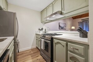 Eine Küche mit einem Edelstahl-Kühlschrank, einem Gasherd und Holzboden.