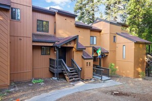 A multi-story residential building with a wooden exterior, a front entrance with steps, and a small porch area. - Two Bears Basecamp | Views, Trails, Flat Parking (Shaver Lake)